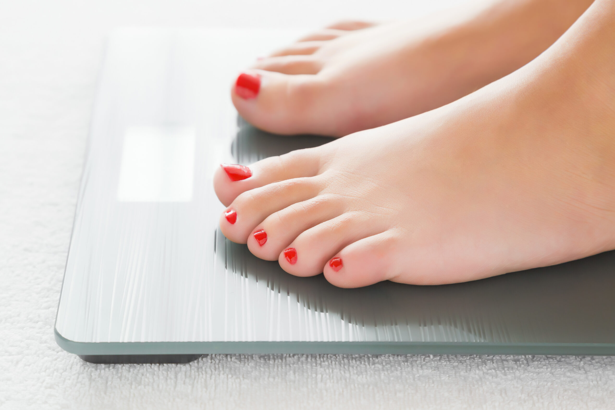 Woman with barefoot standing on the scales. Cares about a body. Weight loss concept. female feet on a scale