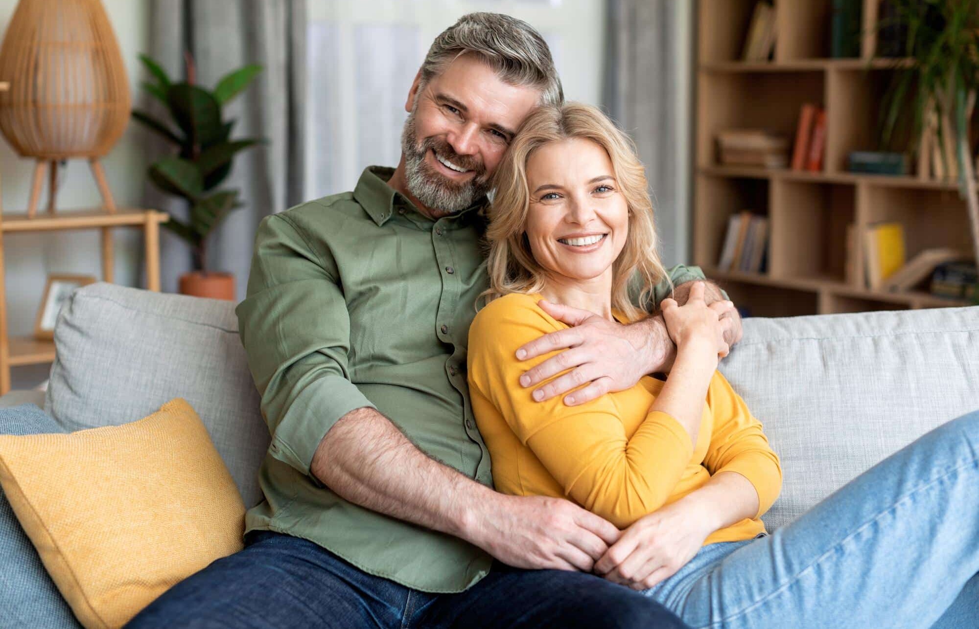 middle aged couple on couch smiling